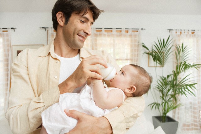 Padre alimentando a su bebé con fórmula infantil
